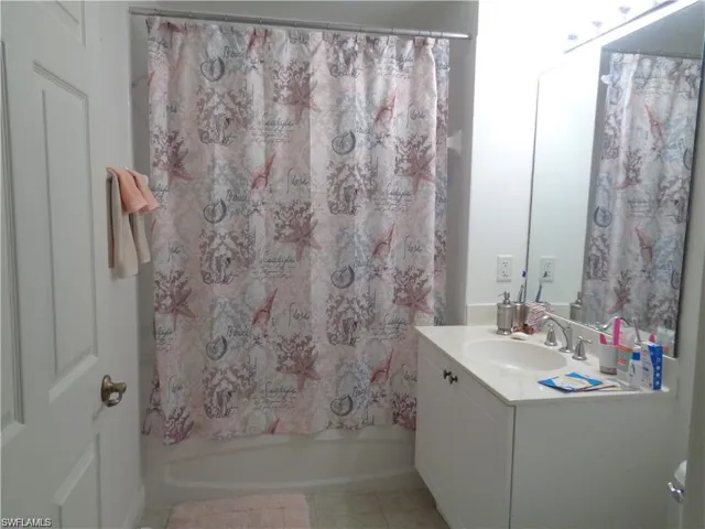 Bathroom with tile floors, vanity, and shower / bathtub combination with curtain
