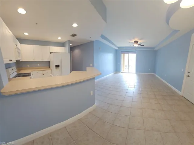 Kitchen featuring white cabinetry, white appliances, kitchen peninsula, ceiling fan, and light tile floors