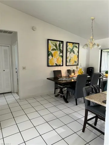 Dining room featuring a notable chandelier, light tile patterned floors, and lofted ceiling