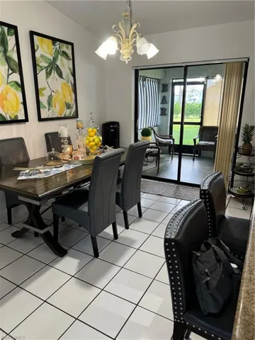 Tiled dining room featuring a notable chandelier and vaulted ceiling