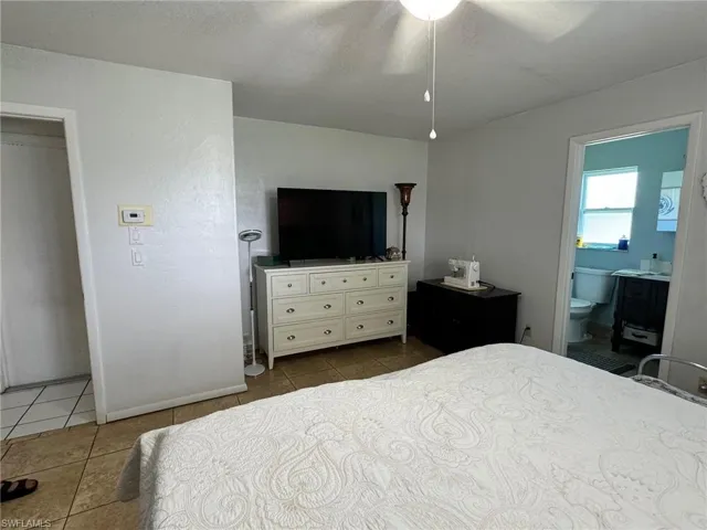 Tiled bedroom with ceiling fan and ensuite bath