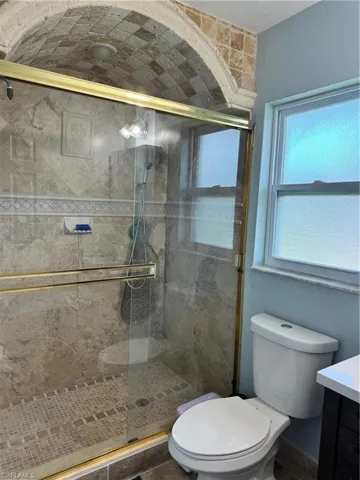 Bathroom with an enclosed shower, vanity, and toilet