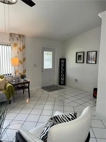 Tiled living room with ceiling fan and lofted ceiling