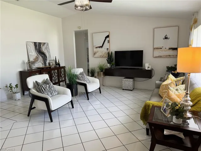 Tiled living room featuring ceiling fan and lofted ceiling