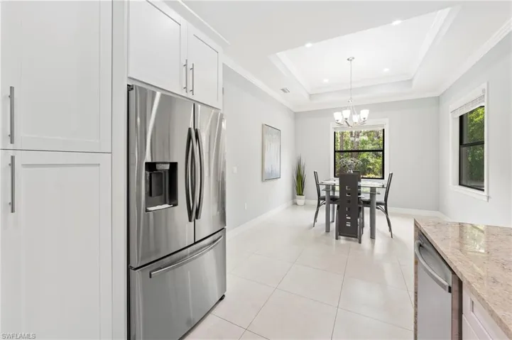 The kitchen features white cabinetry and a stainless steel refrigerator