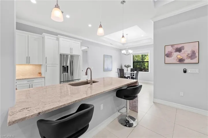 The kitchen features a spacious island with a light-colored countertop, white cabinetry, and stainless steel appliances