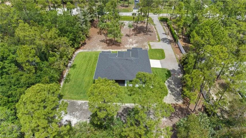 The property features a dark-colored roof, a well-maintained green lawn, and a light-colored driveway