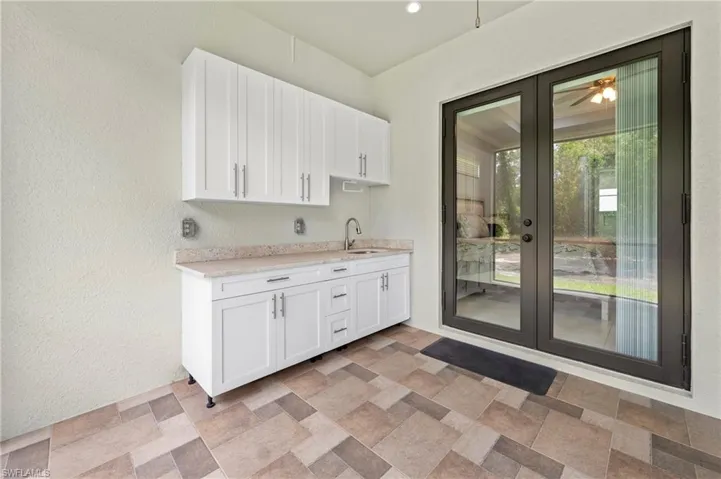 This outdoor space features a full kitchen with white cabinetry and a light-colored countertop