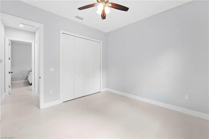 The room features light-colored carpeting, a ceiling fan with light fixture, and a white bi-fold closet