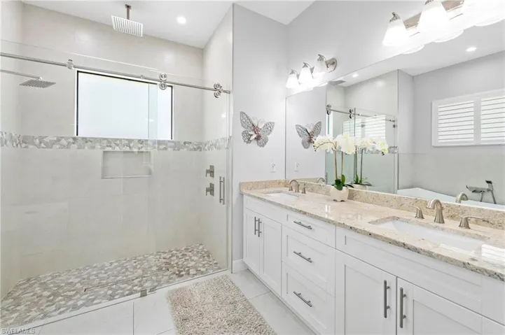 The bathroom features a dual vanity with white cabinetry and a light-colored granite countertop
