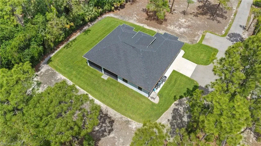 The property features a dark shingled roof, a manicured lawn, and a paved driveway