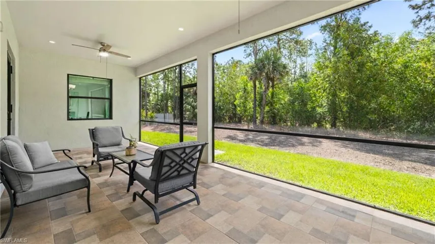 The screened patio features a tiled floor, a ceiling fan, and offers views of lush greenery and mature trees