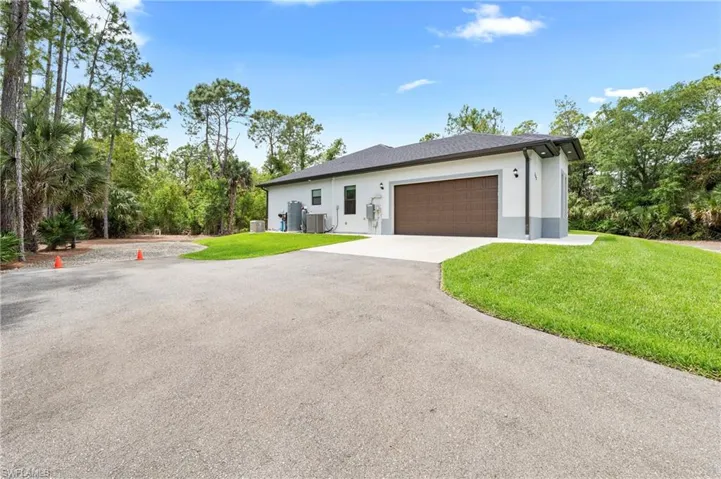 The property features a concrete driveway leading to a two-car garage with a brown door