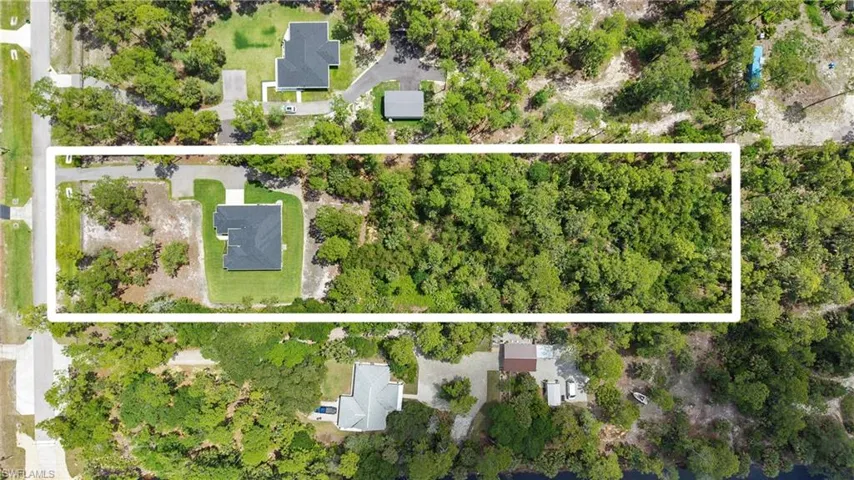 The property features a residence with a dark-colored roof, surrounded by green landscaping and mature trees