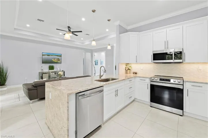 The kitchen features white cabinetry, granite countertops, and stainless steel appliances, including an oven, microwave, and dishwasher