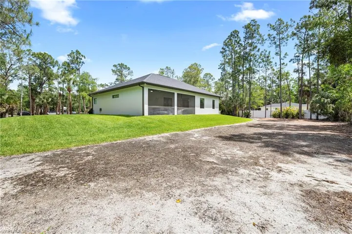 This property features a spacious yard with a well-maintained lawn and mature trees