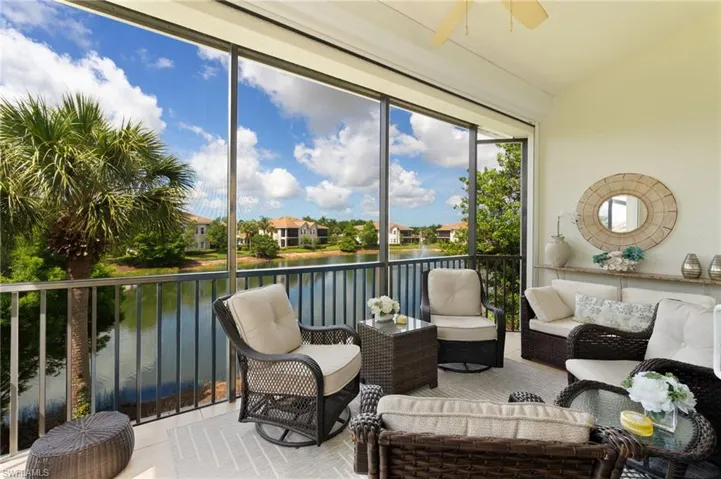 Screened balcony featuring a water backdrop with distant homes, a palm tree, and a vaulted ceiling with a fan