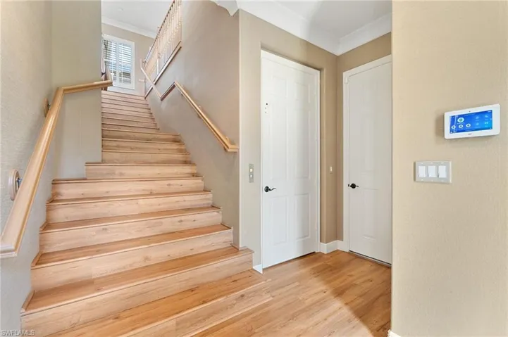 Wood-finish staircase with light-toned treads and risers, complemented by natural wood handrails