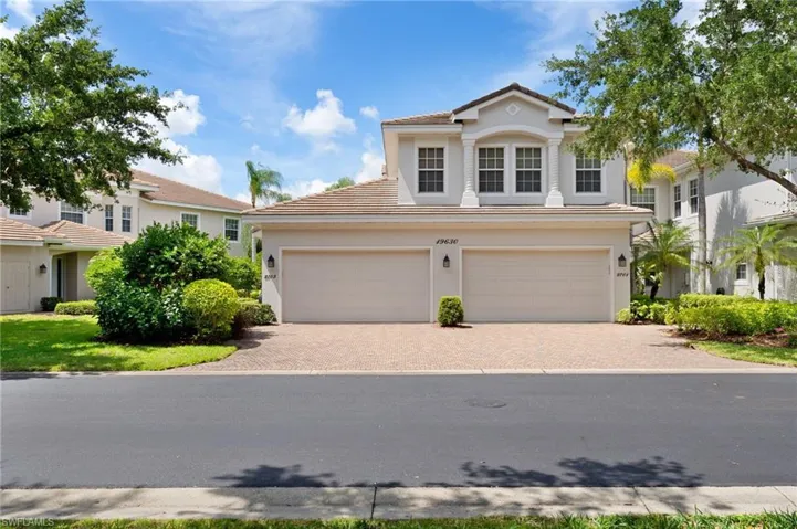 Stucco exterior residence featuring a two-car garage with individual doors, a paver driveway, and an arched entry portico