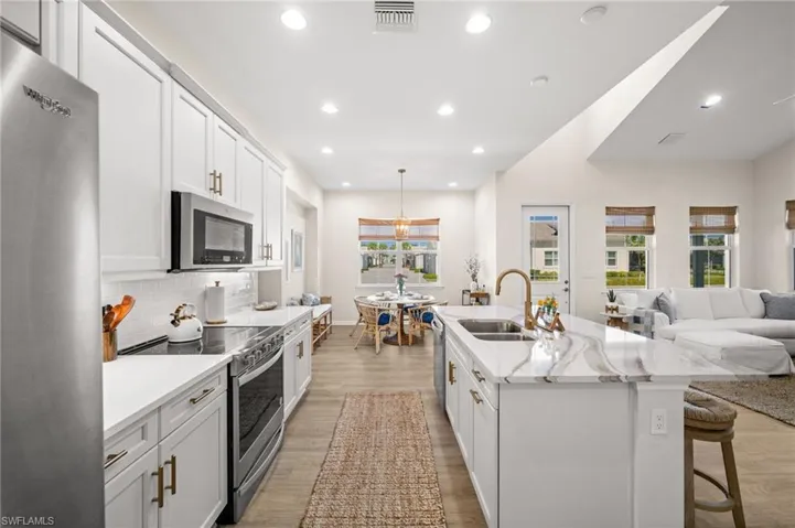 Kitchen with stainless steel appliances, open floor plan, white cabinets, a breakfast bar, and light wood finished floors
