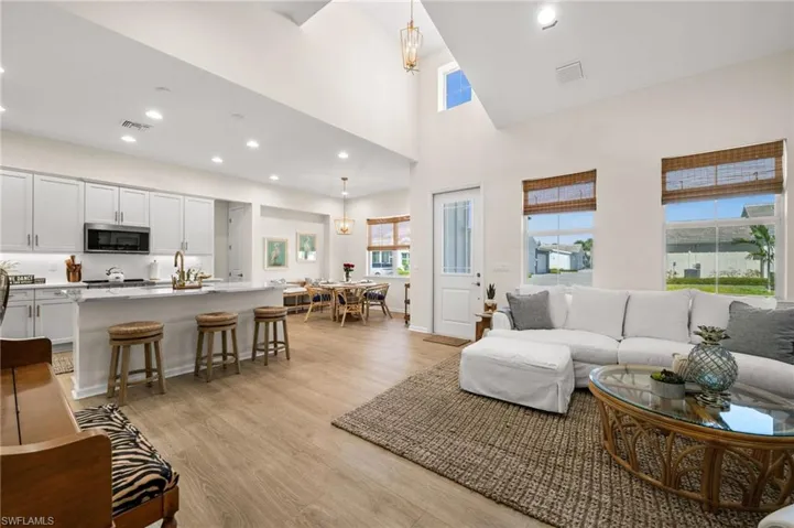 Living room with recessed lighting, a towering ceiling, light wood-style flooring, and a chandelier