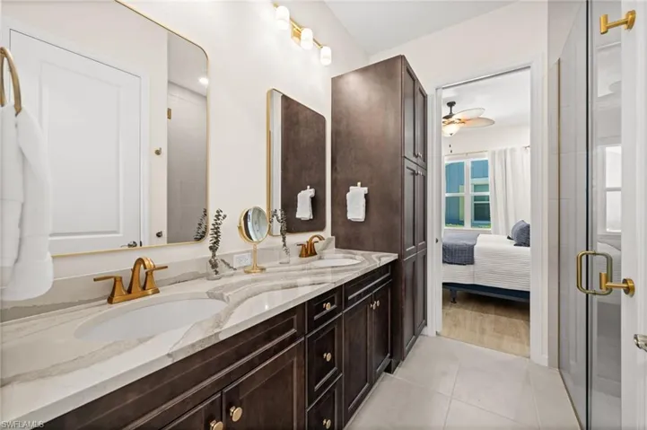 Bathroom featuring double vanity, light tile patterned flooring, ensuite bathroom, a shower stall, and ceiling fan