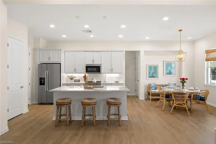 Kitchen with white cabinets, a kitchen breakfast bar, hanging light fixtures, recessed lighting, and appliances with stainless steel finishes