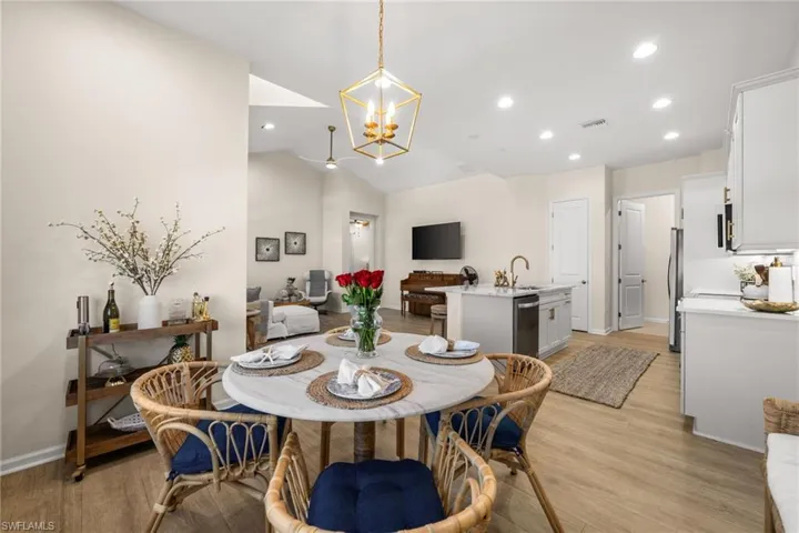 Dining area with vaulted ceiling, light wood-type flooring, recessed lighting, and a chandelier