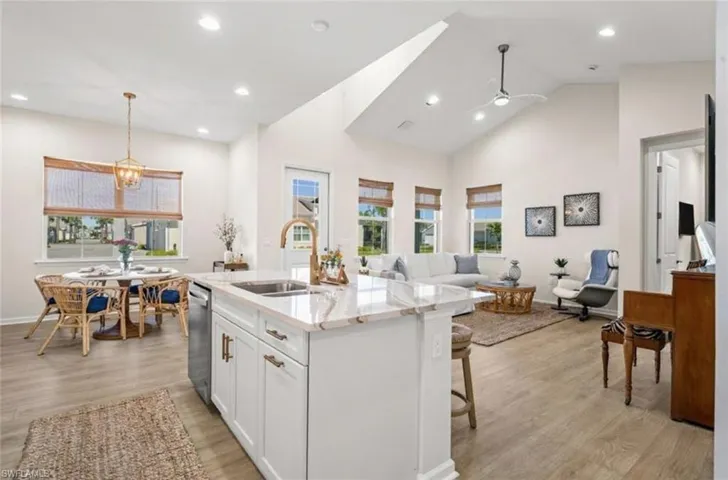 Kitchen with white cabinets, light stone counters, light wood-type flooring, high vaulted ceiling, and recessed lighting