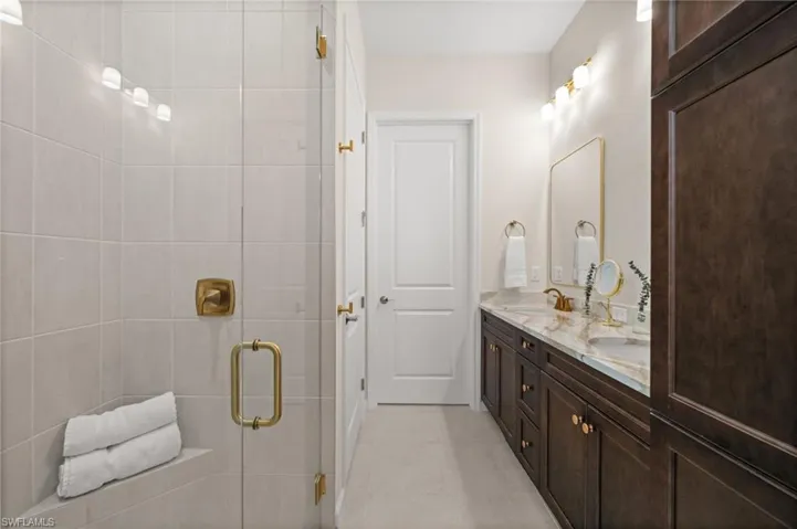 Bathroom featuring double vanity, light tile patterned floors, and a stall shower