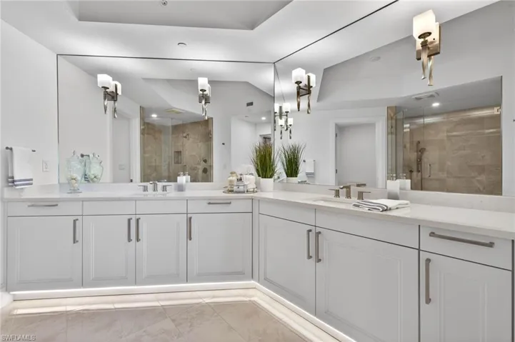 Master Suite Bathroom with a stall shower, double vanity, and light tile patterned floors, elegant sconce light fixtures