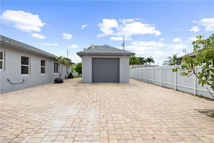 Expansive paver driveway leading to a detached garage with a roll-up door