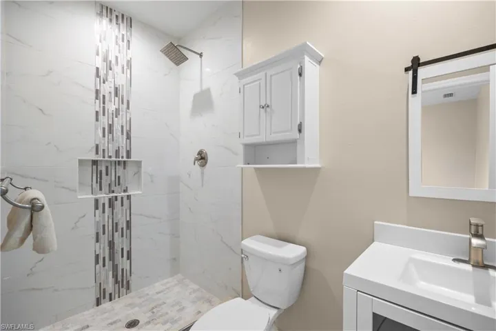 Contemporary bathroom featuring a tiled walk-in shower with a rainfall showerhead, a decorative mosaic tile accent, and a built-in shower niche