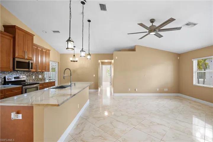 Open-concept kitchen and living area featuring a vaulted ceiling and tile flooring throughout
