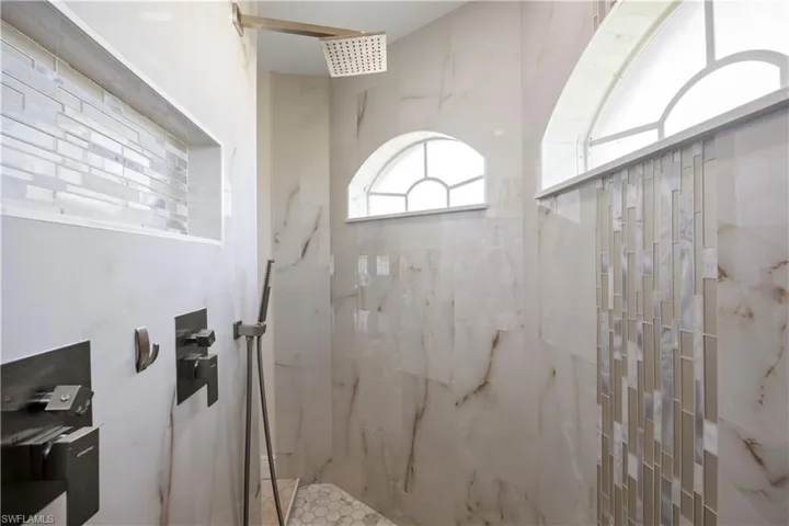 Shower featuring a rain shower head, handheld shower, and integrated storage niches