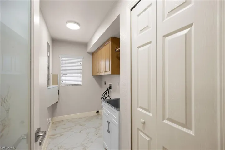 Dedicated laundry area featuring marble-finish tile flooring and neutral wall tones