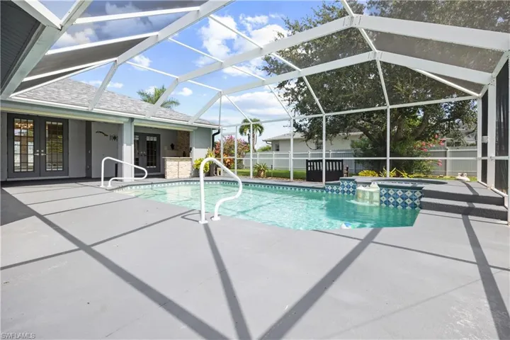 Screened pool enclosure featuring a pool with integrated spa and waterfall