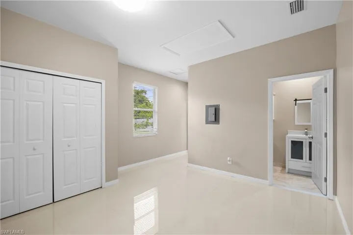 Spacious room featuring light tile flooring, neutral wall tones, and white bi-fold closet doors