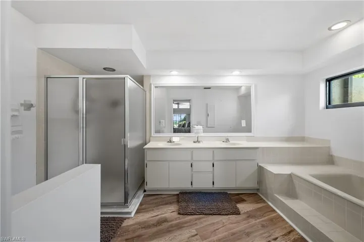 Bathroom with a shower stall, healthy amount of natural light, double vanity, and recessed lighting