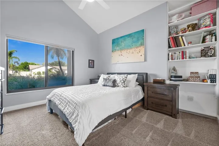 Carpeted bedroom featuring high vaulted ceiling and a ceiling fan