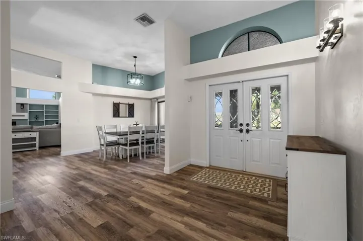 Entrance foyer with wood-type flooring, baseboards, a high ceiling, and a chandelier