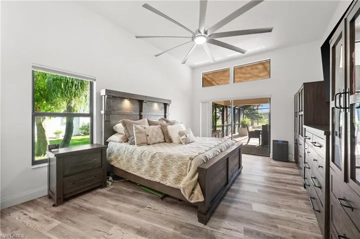 Bedroom with access to exterior, a high ceiling, light wood-type flooring,  and ceiling fan