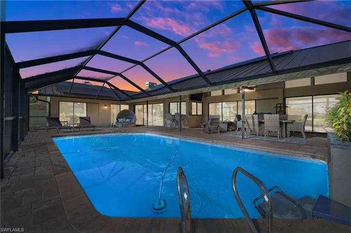 Pool at dusk with a patio, an outdoor pool, and a lanai