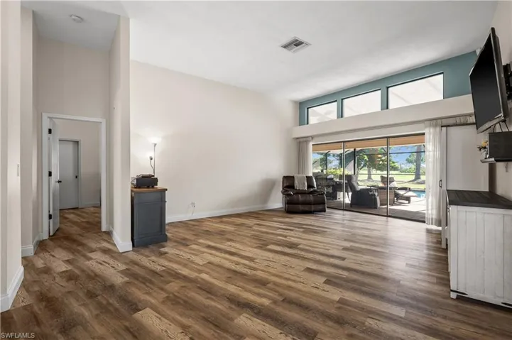 Sitting room featuring dark wood-type flooring, a towering ceiling, and baseboards