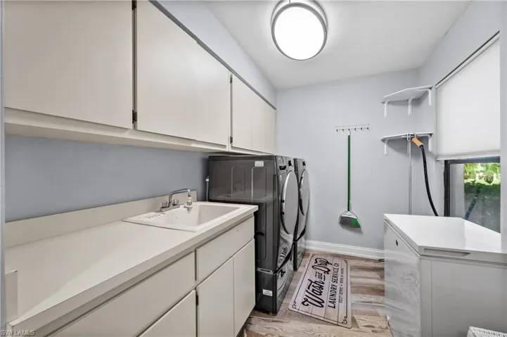 Laundry room featuring washer and clothes dryer, cabinet space, lwood-style flooring