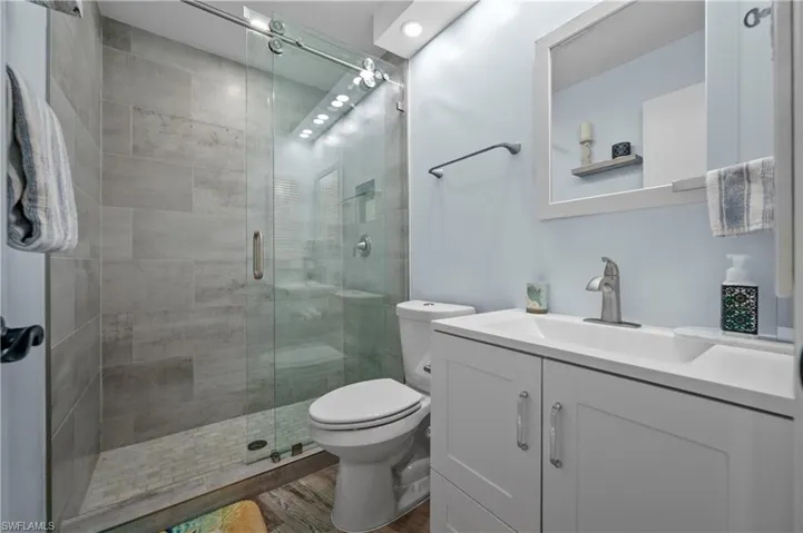 Full bathroom featuring a stall shower, toilet, wood finished floors, and vanity