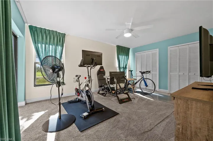 Exercise room with carpet flooring, a ceiling fan