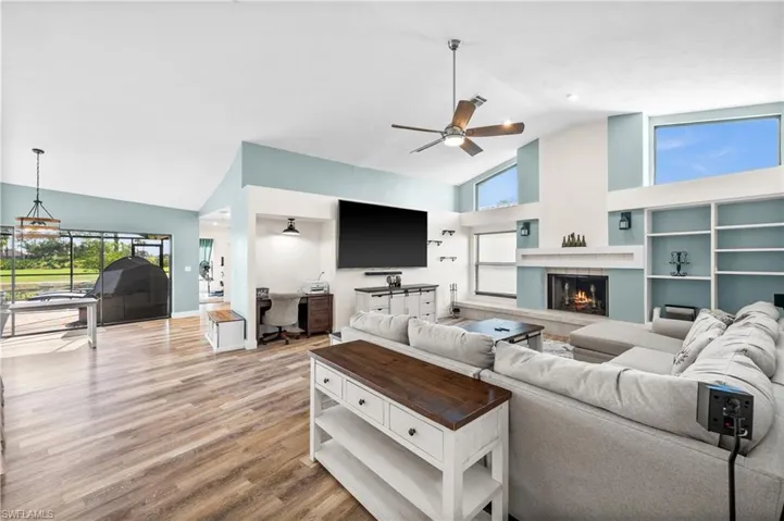 Living area with high vaulted ceiling, wood finished floors, a ceiling fan, and a fireplace