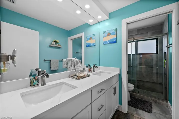 Full bathroom featuring recessed lighting, a shower stall, toilet, double vanity