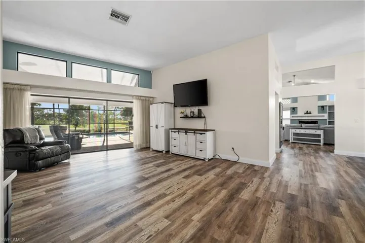 Living area featuring  wood -like finished floors, baseboards, and a towering ceiling